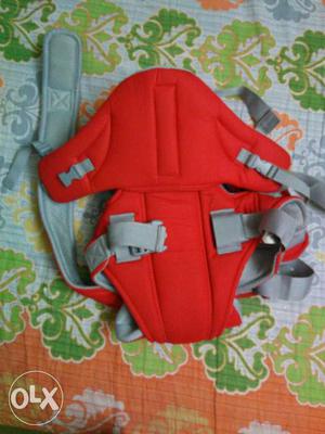 Baby carrier with hood and cushion base for baby.