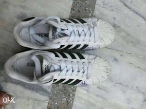Pair Of White And Black Adidas Superstar Sneakers
