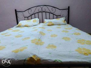 Black Metal Bed With Yellow And White Floral Bed Linen
