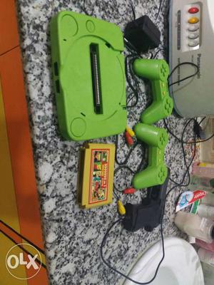 Green Game Console With Gamepads And Game Cartridge