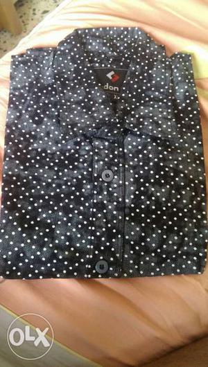It is a black Color shirt with polka dots on it.