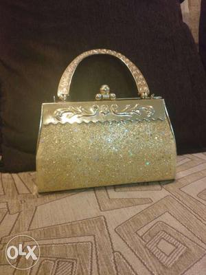 Party wear golden clutch with single handle..