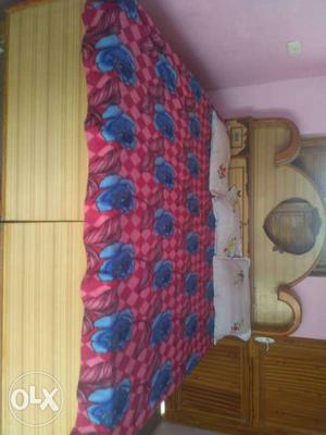 Brown Wooden Bed With Blue And Red Floral Bedspread