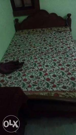Brown Wooden Bed With White And Red Floral Bed Sheet