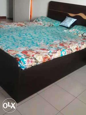 Black Wooden Bed Frame With Teal, White, And Brown Floral