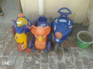 Three Yellow, Blue, And Orange Trike Toys