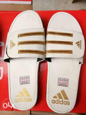 Pair Of White And Gold Adidas Slide On Sandals