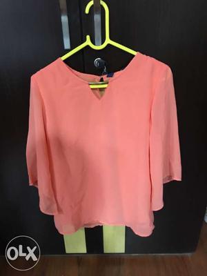 Brand new orange top with price tag attached.