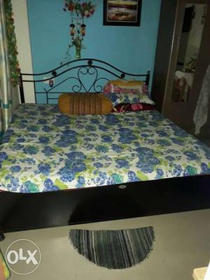 Black Wooden Bed With Blue-and-green Floral Bedsheet
