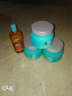 Three Teal Plastic Canisters With Brown Liquid Bottle