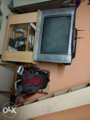 Grey CRT Television; Red And Grey Backpack; Beige Wooden TV
