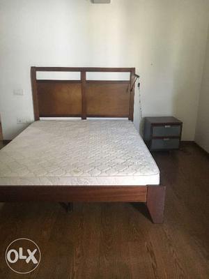Queen size bed with mattress and side table.
