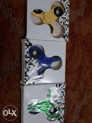 Three Yellow, Blue, And Green Hand Spinners In Boxes
