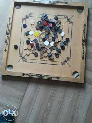 A wooden caroom board with 3 sets of coins