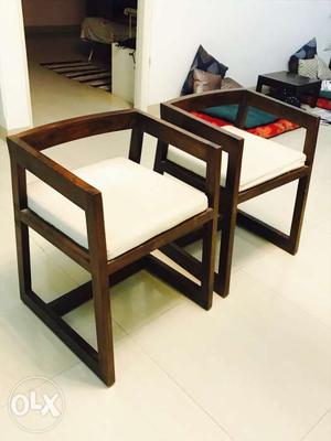 Pair of unused wooden chairs with seat cushions