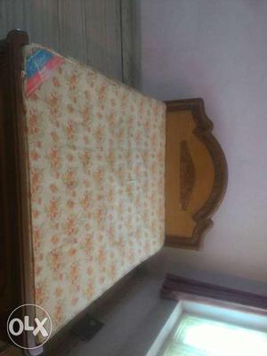 Double bed with a wooden panel and one red floral mattress