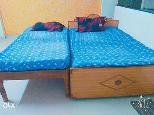 Two Brown Wooden Beds And Two Blue Floral Bedspreads