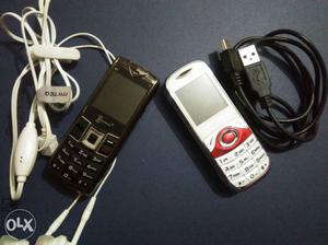 Two Black And White Candybar Phones With White Earbuds And