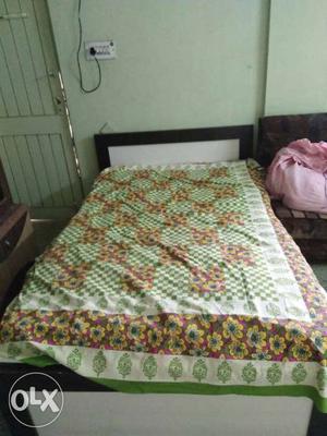 White Upholstered Bed With Green Floral Bed Sheet