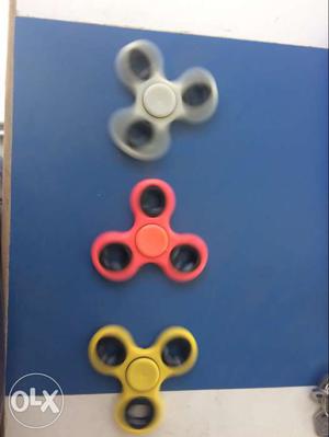 Three White, Red, And Yellow Fidget Hand Spinners