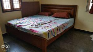 Brown Wooden Bed And Pink, Blue, And Yellow Bed Spread