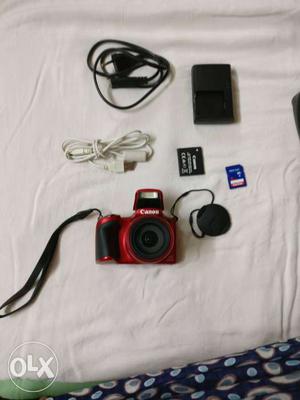 Red Canon Compact Camera With Battery Charger And Connectors