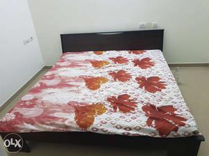 White And Red Floral Bedspread And Black Wooden Bed Frame
