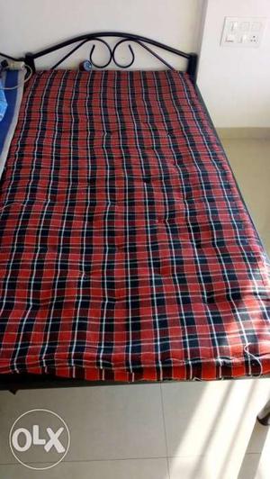 Steel cot and red and black checkered mattress