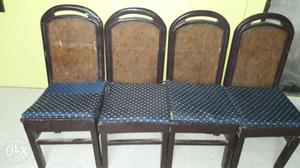 Four Brown Wooden Framed Black Padded Armless Chairs