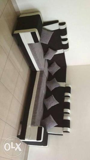 Black And White Corner Sofa With Several Gray Throw Pillows