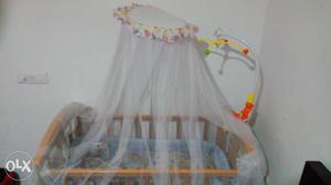 Baby's Brown Wooden Crib With White Mosquito Net.