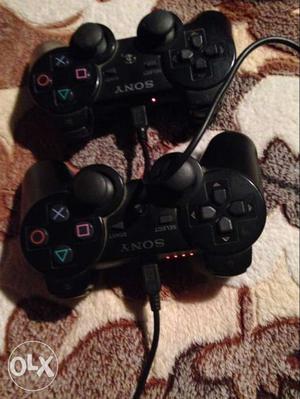 Two Black Sony Game Controllers