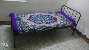 Black Metal Bed With Purple And Beige Floral Bedspread
