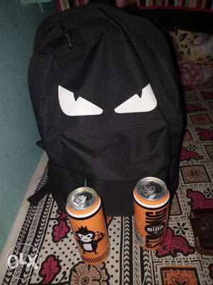 Two Orange Beverage Cans And Black Backpack