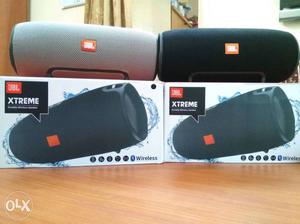 Two Gray And Black JBL Xtreme Speakers With Box