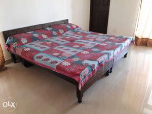 Brown Wooden Bed With Red And Multicolored Floral Bedspread