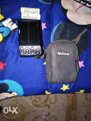Black Nikon Point-and-shoot Camera With Gray Bag