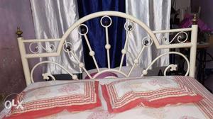 White Metal Bed Frame And White, Red, And Beige Pillows