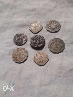 Five Silver-colored And Two Black Indian Paise Coins