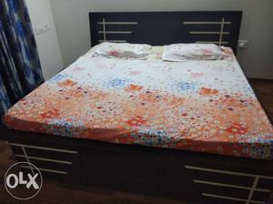 Brown Wooden Bed Frame With White And Red Floral Bedspread