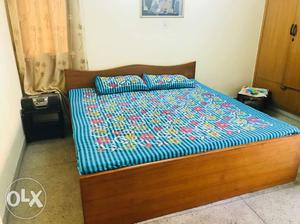Brown Wooden Bed And Blue, Red, And Yellow Floral Bed Sheet