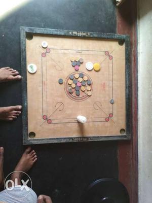 Carrom board with 3white coins 2black coins and