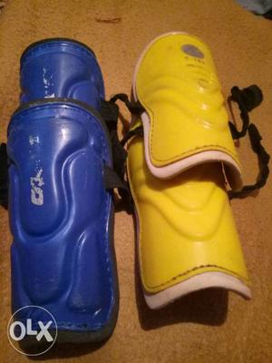 Two Pairs Of Blue And Yellow Shin Guards
