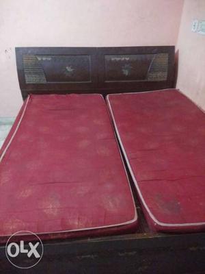 Two Red Bed Mattresses And Brown Wooden Bed