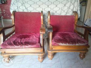 Two Red Padded Armchairs With Brown Wooden Frames