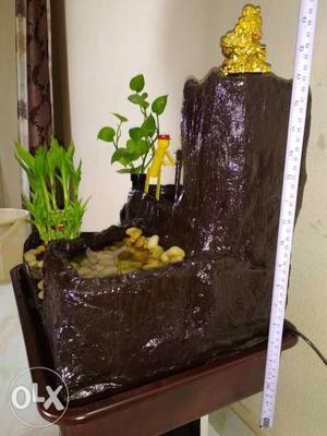Brown water fountain with stones..greenery ang