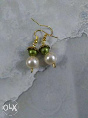 A earring made of white beads and green beads.