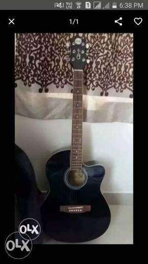 Black acoustic guitar with bag and a belt.