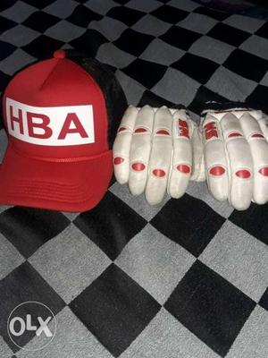 Red And Black Cap And Pair Of White Cricket Gloves