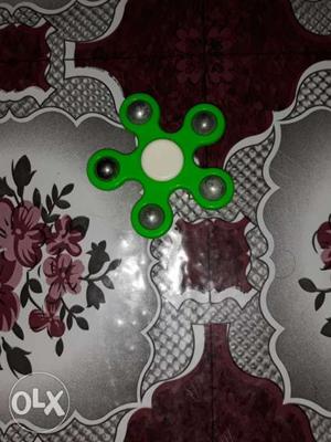 Green And White 5-blade Fidget Spinner Placed On Gray And